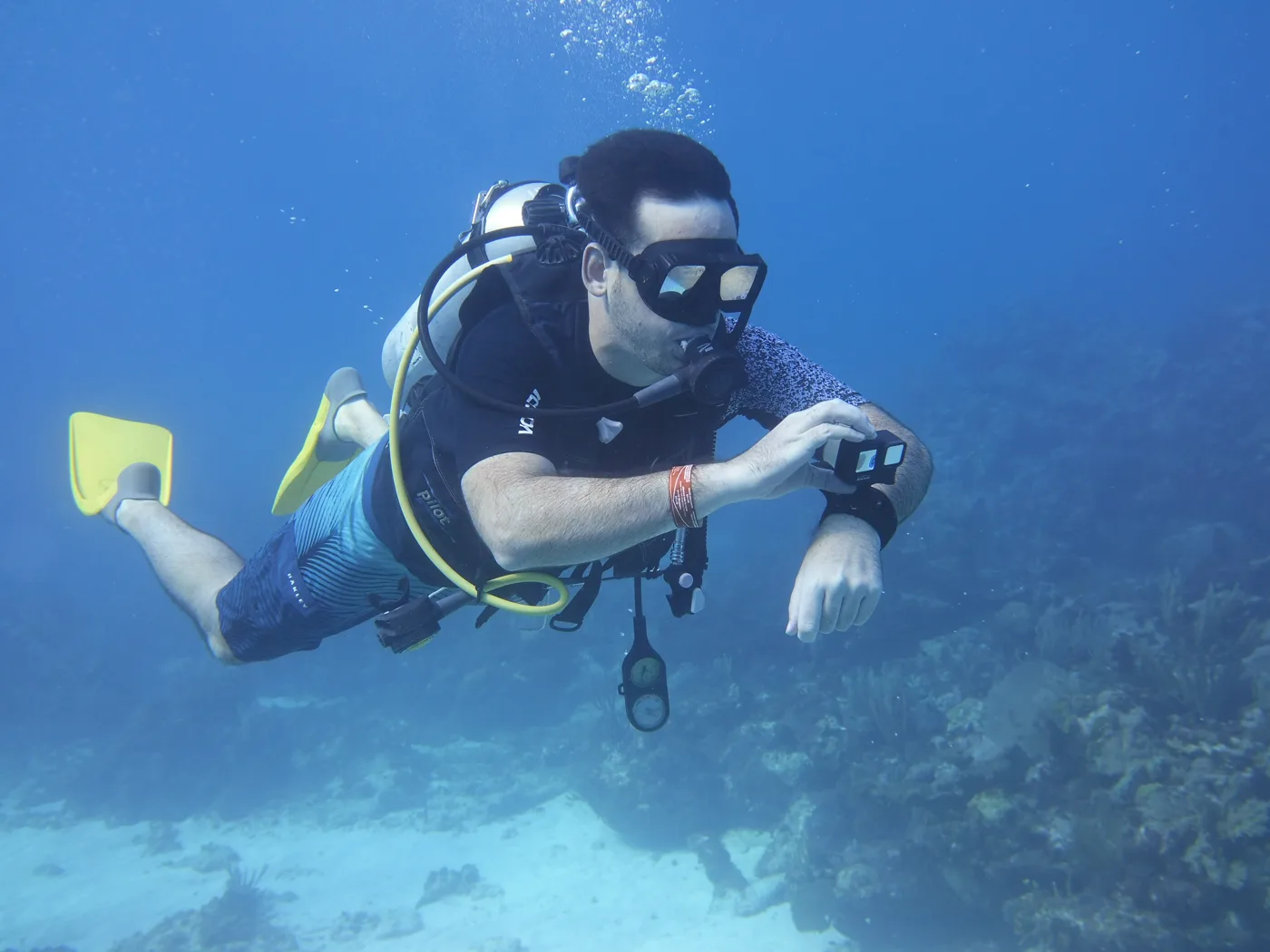 Ryan scuba diving with a GoPro over a coral reef