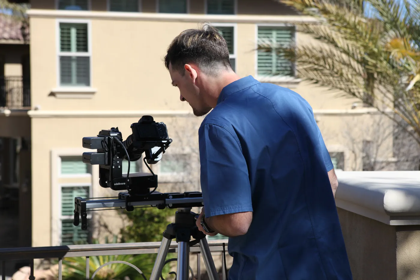Ryan operating a camera on a slider rig on a sunny balcony