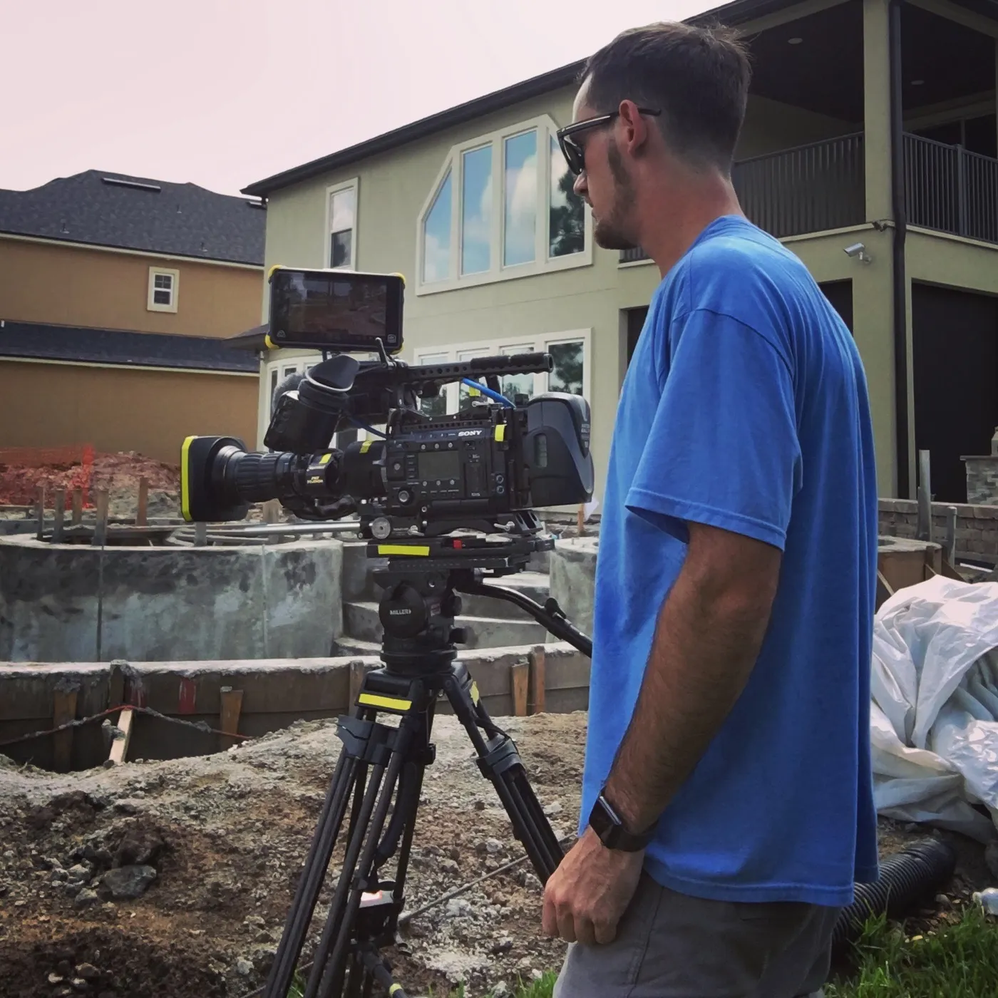 Ryan beside a Sony cinema camera on a tripod at a backyard construction site