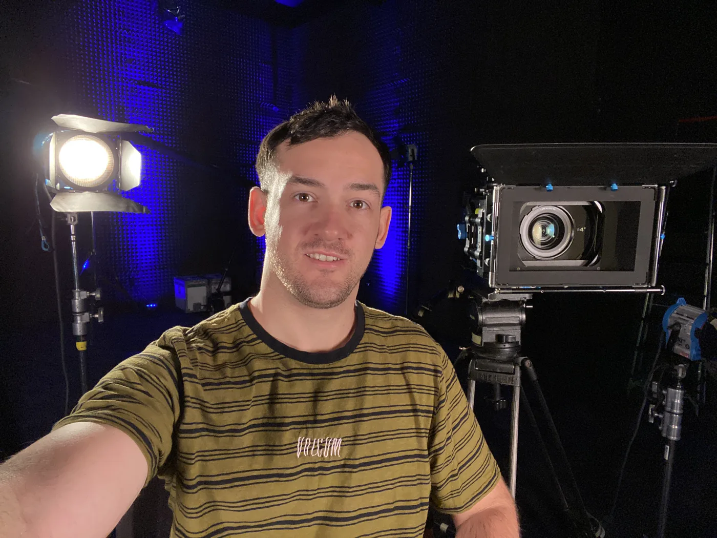 Ryan Dundas in a darkened studio beside a cinema camera and softbox lighting